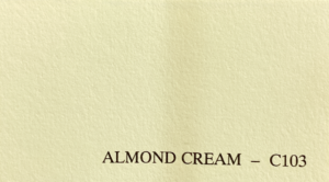 A textured paper sample displays a soft, cream color labeled "ALMOND CREAM - C103" in the bottom right corner, suggesting a gentle, warm tone.